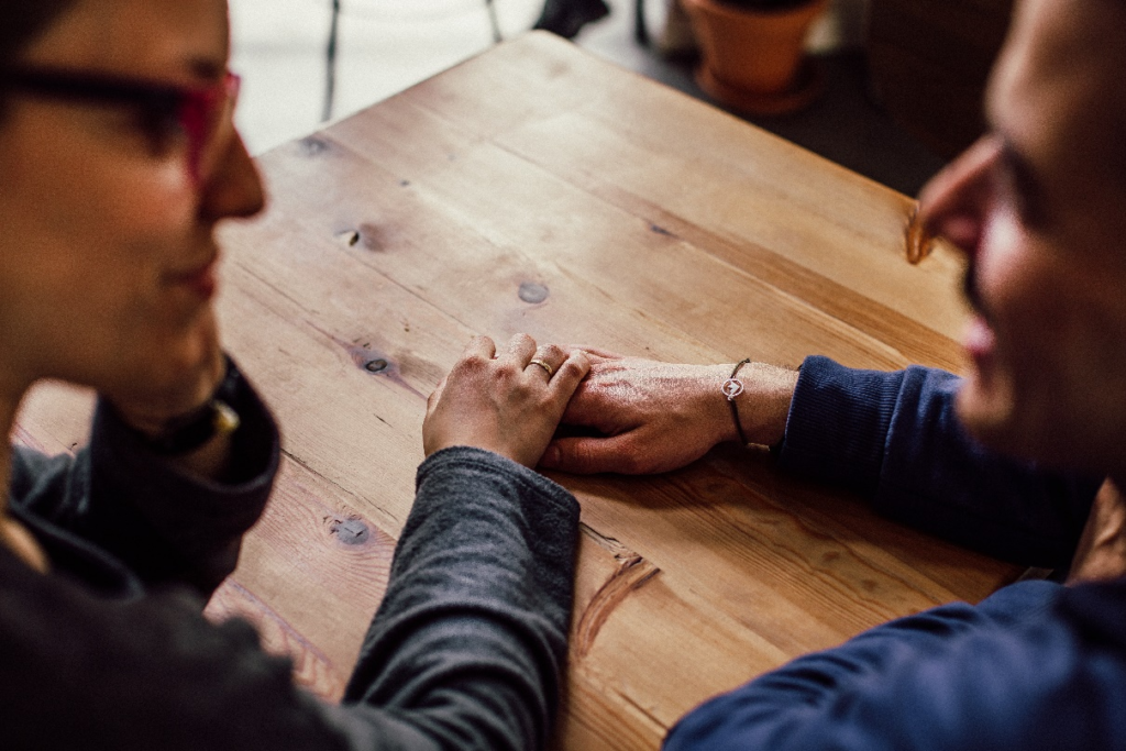 Two people sitting and talking while holding each other hands.