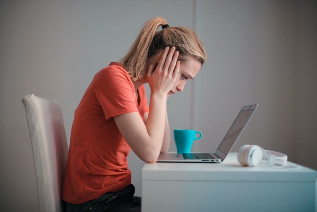 A worried woman sitting looking at her laptop