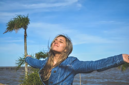 a woman standing with her arms out by the sea