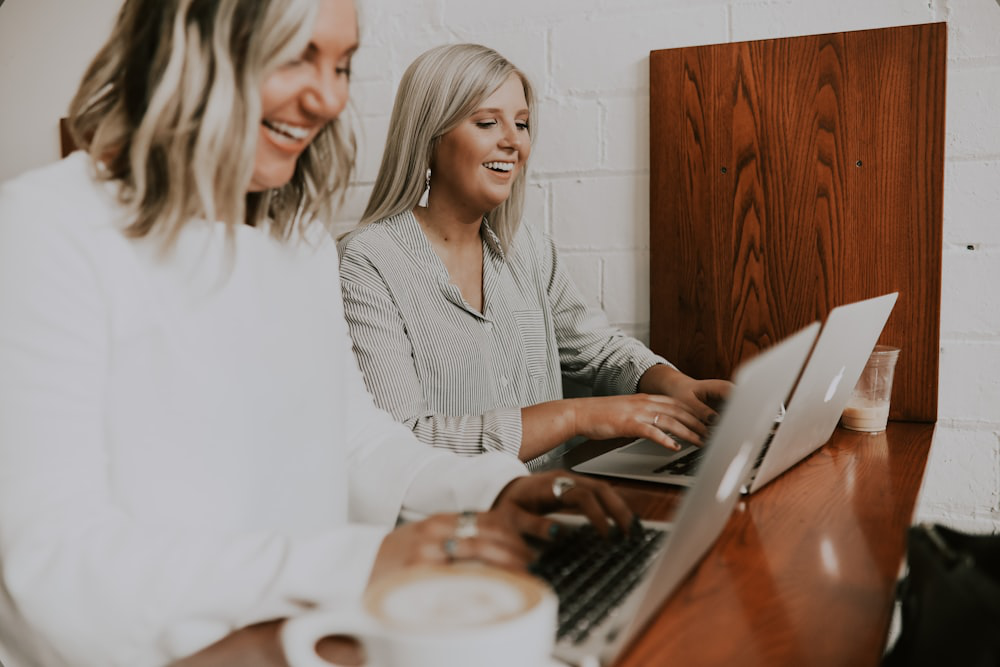 Two Laughing Employees, Having Discovered Stress-free Ways to Work, Tap Away at Their Laptops