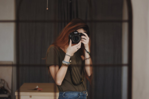 A girl capturing her picture in the mirror using a DSLR.