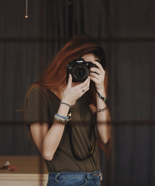 A girl capturing her picture in the mirror using a DSLR.