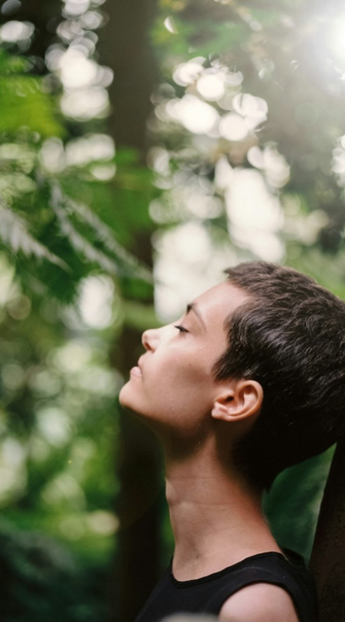 A Woman Explores the Power of Mindfulness by Leaning Against a Tree Facing the Sky